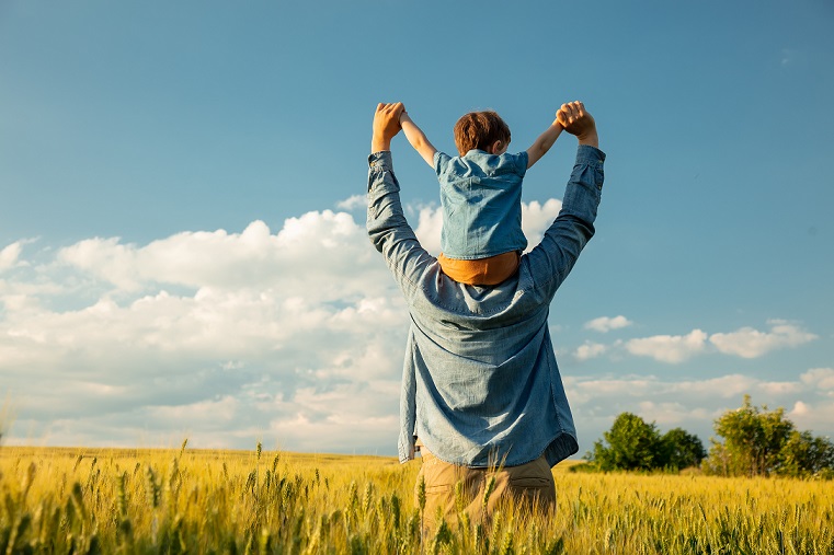 father and son in wheat field, child sitting on his fathers shoulders