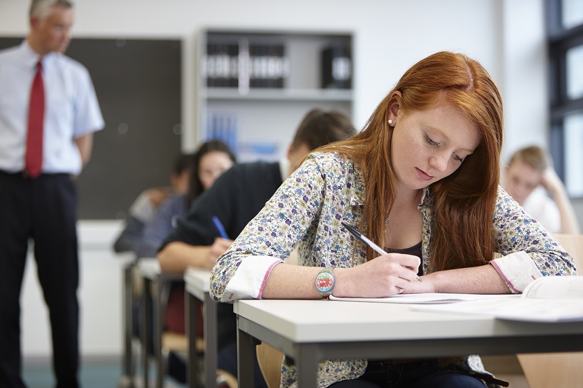 Teacher watching over teenagers in classroom