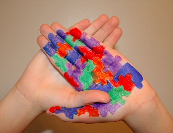 Autism Awareness. colourful jigsaw painted onto crossed child's hands