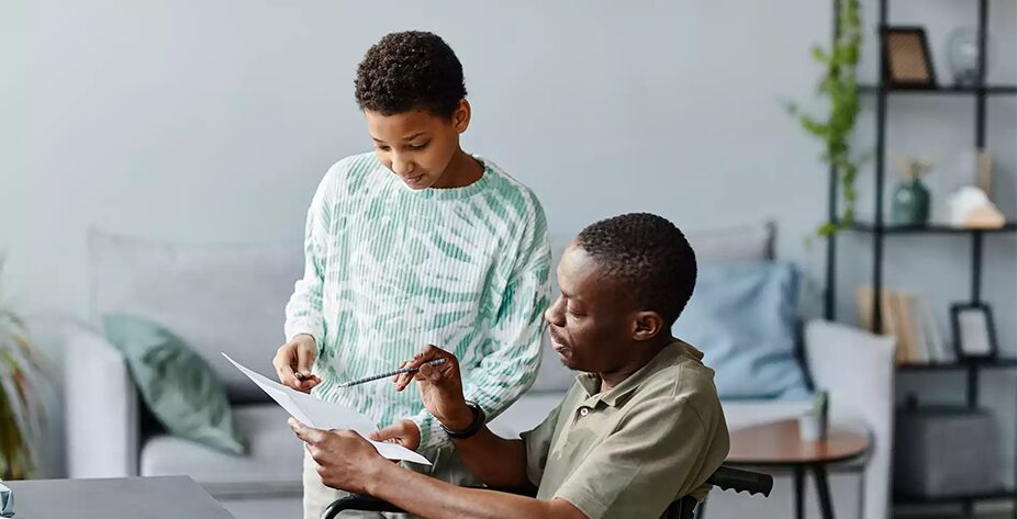 father-in-wheelchair-helping-daughter-with-home-work