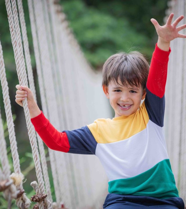 Child on rope bridge, holding his hand to the air