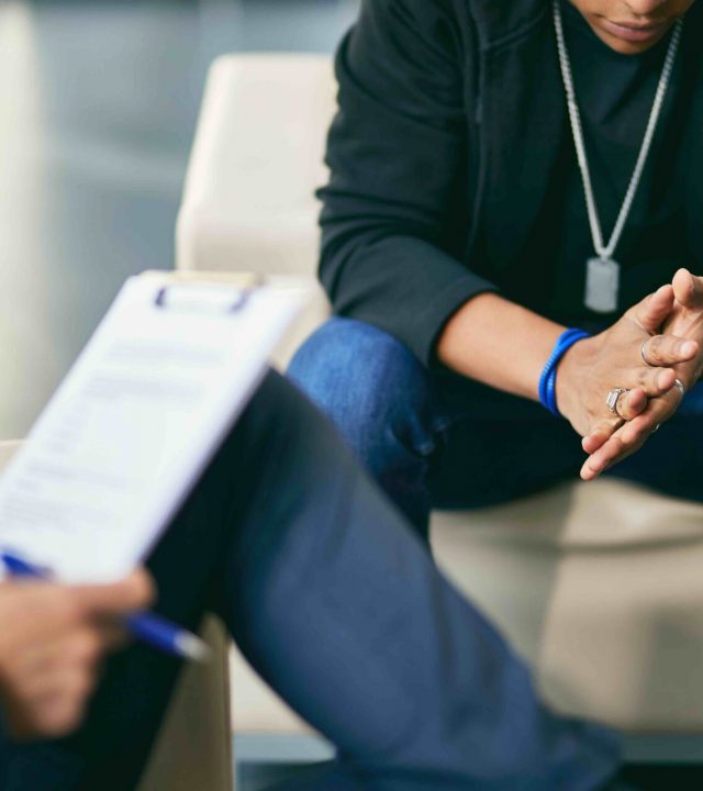 Close-up of black teenage boy having counselling with psychotherapist.